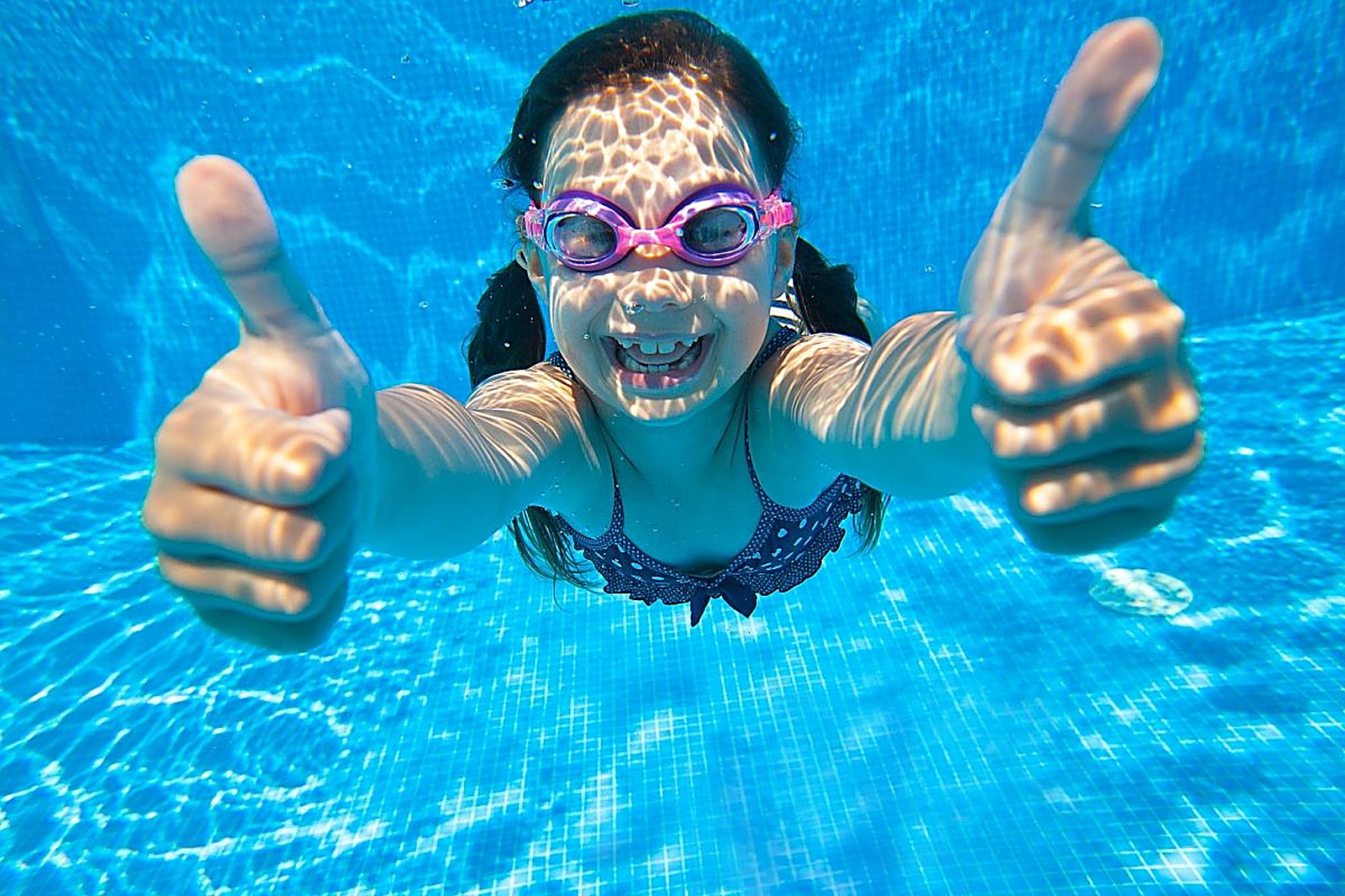 Child giving thumbs up underwater
